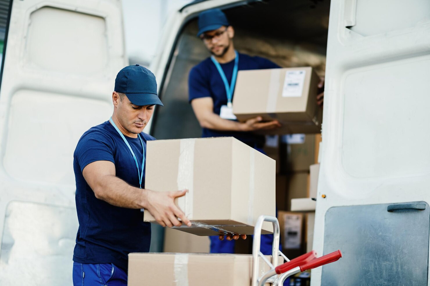 joven-mensajero-su-colega-descargando-cajas-carton-furgoneta-reparto